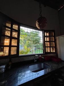 a kitchen with a sink and two windows at Granja Raio de Luz in Igarassu