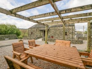 una mesa de madera y sillas en un patio en Cherry Tree Barn en Ulverston