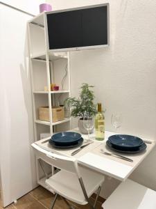 a white table with two blue plates and a tv at Casa Manú centro Bologna in Bologna