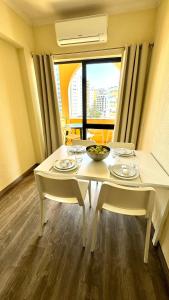 una mesa blanca con dos sillas y una mesa con gafas. en Praia da Rocha, 5-F, Charming Apartment with Air Conditioning - Pátio da Rocha By IG, en Portimão