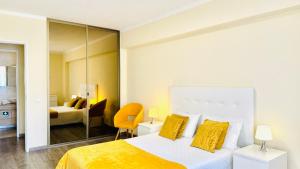 1 dormitorio con 1 cama con almohadas amarillas en Praia da Rocha, 5-F, Charming Apartment with Air Conditioning - Pátio da Rocha By IG, en Portimão
