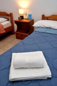a bed with a white towel on it next to a desk at Maria Konstantinidis Apartments in Nea Potidaea