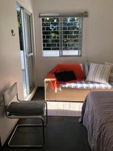 uma cama e uma cadeira num quarto com uma janela em Opera Hostel em Curitiba