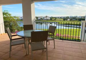 a patio with a glass table and chairs on a balcony at Apartment with pool & golf views - ER2113LT in Roldán