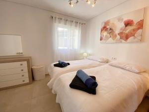 Dos camas en un dormitorio blanco con toallas. en Beautiful sunny penthouse pool views - RA2532LT, en Los Tomases