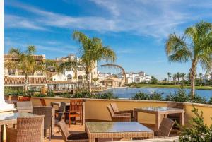 un complexe avec des tables et des chaises et une vue sur l'eau dans l'établissement Apartment with pool & golf views - AA2711LT, à Roldán