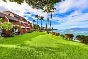a resort lawn with palm trees and the ocean at Kuleana Resort 104 in Kahana