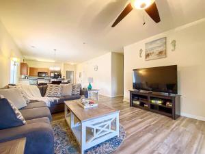 a living room with a couch and a flat screen tv at Lakefront at Barefoot Resort w Massive Waterfront Pool Close to Beach in North Myrtle Beach