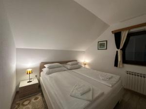 a bedroom with a bed with two white towels on it at Apartment Rosandić in Smoljanac