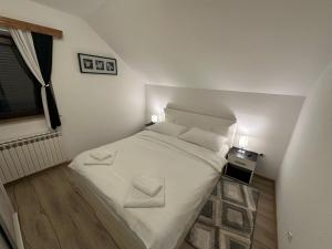 a small bedroom with a bed with white sheets and pillows at Apartment Rosandić in Smoljanac