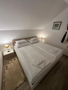 a bedroom with a large bed with white sheets and pillows at Apartment Rosandić in Smoljanac