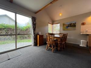een eetkamer met een tafel en een groot raam bij 15 Caverhill Close in Hanmer Springs