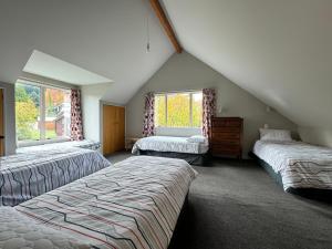 een slaapkamer op zolder met 2 bedden en 2 ramen bij 15 Caverhill Close in Hanmer Springs