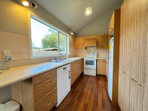 een keuken met houten kasten en een raam bij 15 Caverhill Close in Hanmer Springs +11 foto's