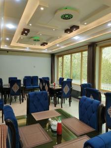 una sala de conferencias con sillas azules, mesas y ventanas en North Palace Khaplu, en Khaplu