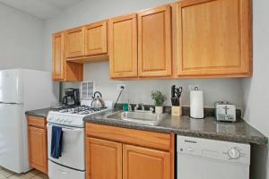 cocina con armarios de madera y horno de fogón blanco en Comfortable Studio Hideaway in Evanston - Elmgate Manor 317, en Evanston