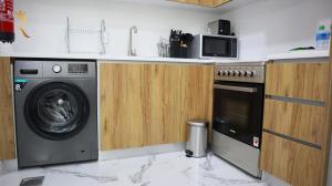 a kitchen with a washing machine and a microwave at Duplex Serenity: Your 2BR Transit apartment. in Abu Dhabi