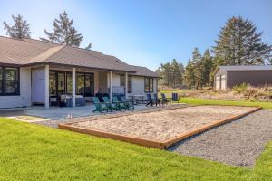 a house with a patio and a yard with chairs at Gearhart Getaway - Gated Community Home w/ Hot Tub, Walk to Beach in Warrenton