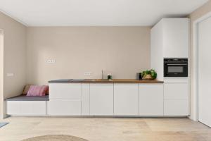uma cozinha com armários brancos e um forno com placa de fogão em Hello Zeeland - Appartement Duinenburg 10- 3 em Domburg