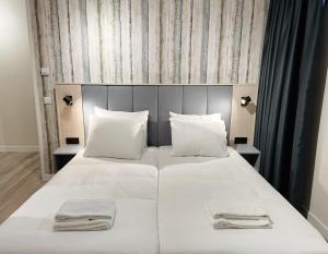 een groot wit bed met 2 handdoeken erop bij Hello Zeeland - Appartement Duno Lodge I in Oostkapelle