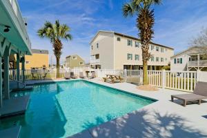 une piscine bordée de palmiers et un bâtiment dans l'établissement Tropical Rays Huge Cherry Grove House w Pool, à Myrtle Beach