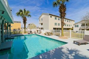 a swimming pool with palm trees and a building at Tropical Rays Huge Cherry Grove House w Pool in Myrtle Beach