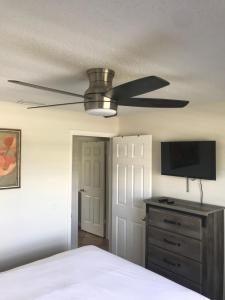 a bedroom with a ceiling fan and a dresser with a television at Kelli’s Sunset Getaway in Melbourne