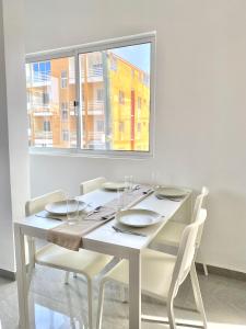 a white dining room table with chairs and a window at Vila de Santiago Apartment in Pedra Badejo