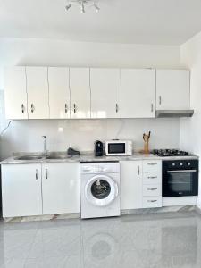 a kitchen with white cabinets and a washing machine at Vila de Santiago Apartment in Pedra Badejo