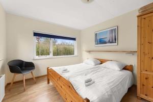 ein Schlafzimmer mit einem Bett, einem Stuhl und einem Fenster in der Unterkunft Hello Zeeland - Vakantiehuis Oosterpark 92 in Oostkapelle