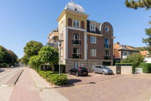 a large building with a clock tower on a street at Hello Zeeland - Appartement Domburgseweg 11-2 in Domburg