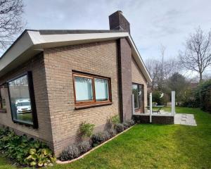 een stenen huis met ramen en een grasveld bij Hello Zeeland - Vakantiehuis Oosterpark 92 in Oostkapelle