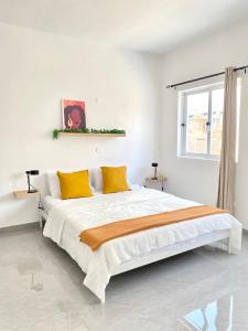 a white bedroom with a large bed with yellow pillows at Vila de Santiago Apartment in Pedra Badejo