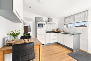 a kitchen with white cabinets and a wooden table at Hello Zeeland - Vakantiehuis Zuidstraat 17A in Domburg