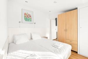 een slaapkamer met een wit bed en een houten kast bij Hello Zeeland - Vakantiehuis Zuidstraat 17A in Domburg