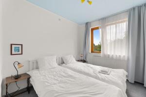 een slaapkamer met 2 witte bedden en een raam bij Hello Zeeland - Vakantiehuis Weststraat 13A in Domburg