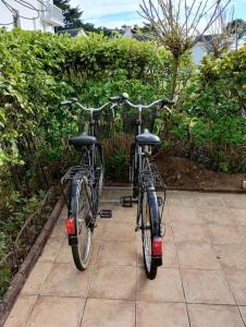 zwei Fahrräder, die nebeneinander auf einem Bürgersteig geparkt sind in der Unterkunft Appartement avec terrasse in Quiberon