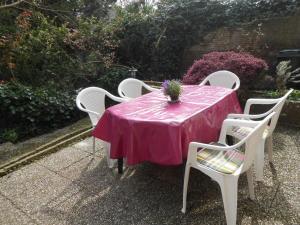 une table rose avec des chaises blanches et une plante en pot dans l'établissement Hello Zeeland - Vakantiehuis Weststraat 13A, à Domburg