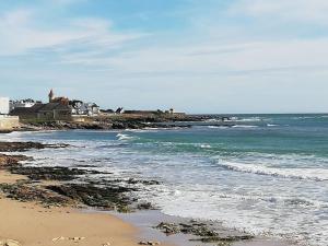 einen Strand mit dem Meer und einem Leuchtturm in der Ferne in der Unterkunft Appartement avec terrasse in Quiberon