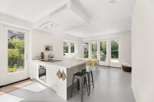 a white kitchen with a large island with stools at NEW Hello Zeeland - Vakantiehuis Jhr De Casembrootplein 19 in Domburg