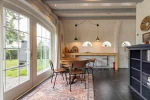 a dining room with a table and chairs and windows at De Kleine Schuur at Buitenplaats Zeeuwse Liefde in Westkapelle