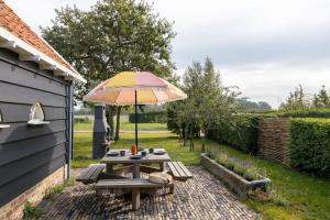 a picnic table with an umbrella on a patio at De Kleine Schuur at Buitenplaats Zeeuwse Liefde in Westkapelle