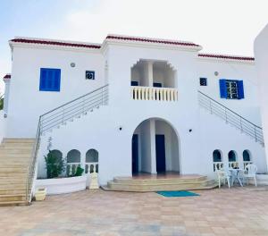 a white house with a staircase in front of it at Résidence Karim in Djerba