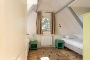 een slaapkamer op zolder met 2 bedden en 2 tafels bij Het Kleine Huis at Buitenplaats Zeeuwse Liefde in Westkapelle