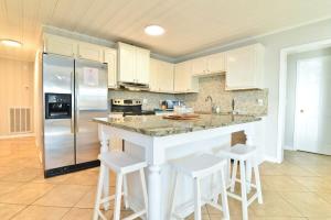 a kitchen with white cabinets and a large island with bar stools at HAZELS CHILD II Beach House DIRECT OCEANFRONT Ocean and Pier Views in Myrtle Beach