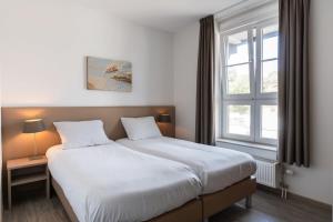 ein Schlafzimmer mit einem großen Bett und einem Fenster in der Unterkunft Hello Zeeland - Duinhof V 1-7 in Cadzand