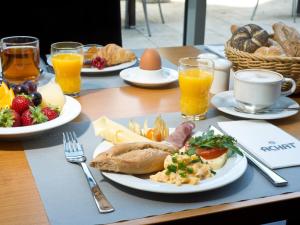 une table avec des assiettes de nourriture et des verres de jus d'orange dans l'établissement ACHAT Hotel Bochum Dortmund, à Bochum