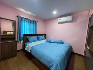 een slaapkamer met een bed met blauwe lakens en een raam bij Manee House - บ้านมณี in Buriram