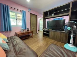 een woonkamer met een ventilator en een televisie bij Manee House - บ้านมณี in Buriram