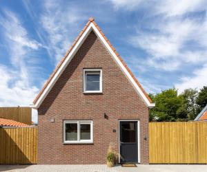 a red brick house with a wooden fence at Hello Zeeland - Vakantiehuis Herenstraat 1A in Domburg